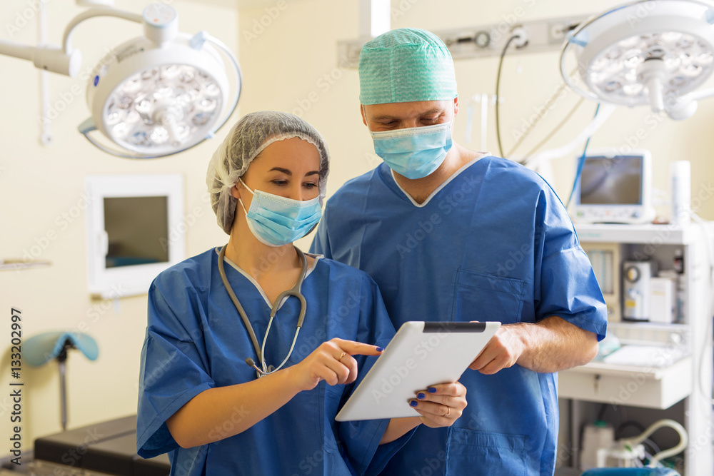 Doctor and his assistant using tablet in surgery room Doctor and his assistant using tablet in surgery room