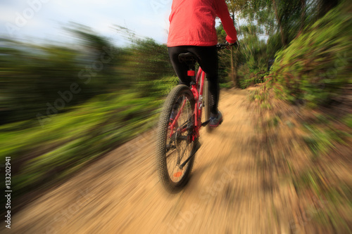 young woman riding bike on forest mountain trail