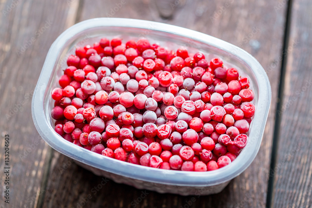 Frozen Cranberries in Container on Wooden Table, Horizontal View Frozen Cranberries in Container on Wooden Table, Horizontal View
