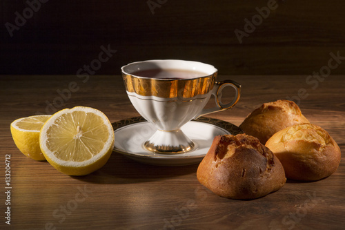Cup of tea with a lemon and sweets. Still life against a dark background