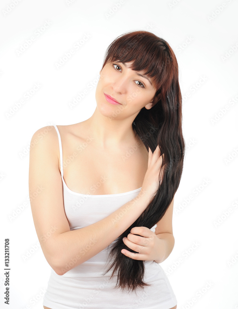 Young long-haired brunette in white shirt on white background touching her hair Young long-haired brunette in white shirt on white background touching her hair