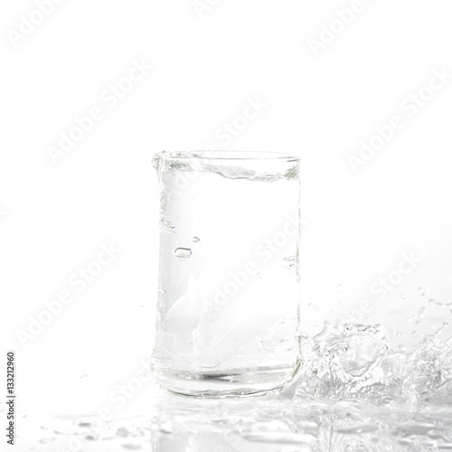 Ice cubes splashing into glass of water isolated on white background