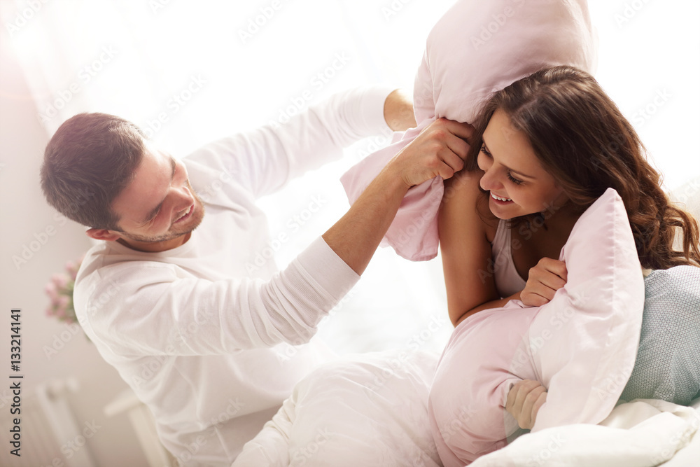 Happy couple having pillow fight Happy couple having pillow fight