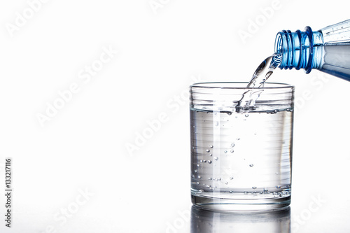 Mineralwasser aus Flasche in Glas eingeschenkt
