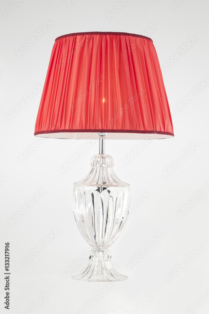 lampada da tavolo in cristallo e paralume in seta rossa, su fondo bianco.