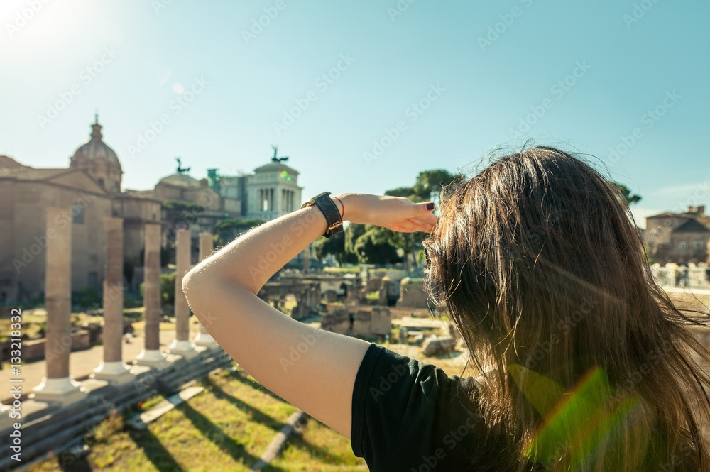 Woman looking forward with hand on forehead to archeological rui