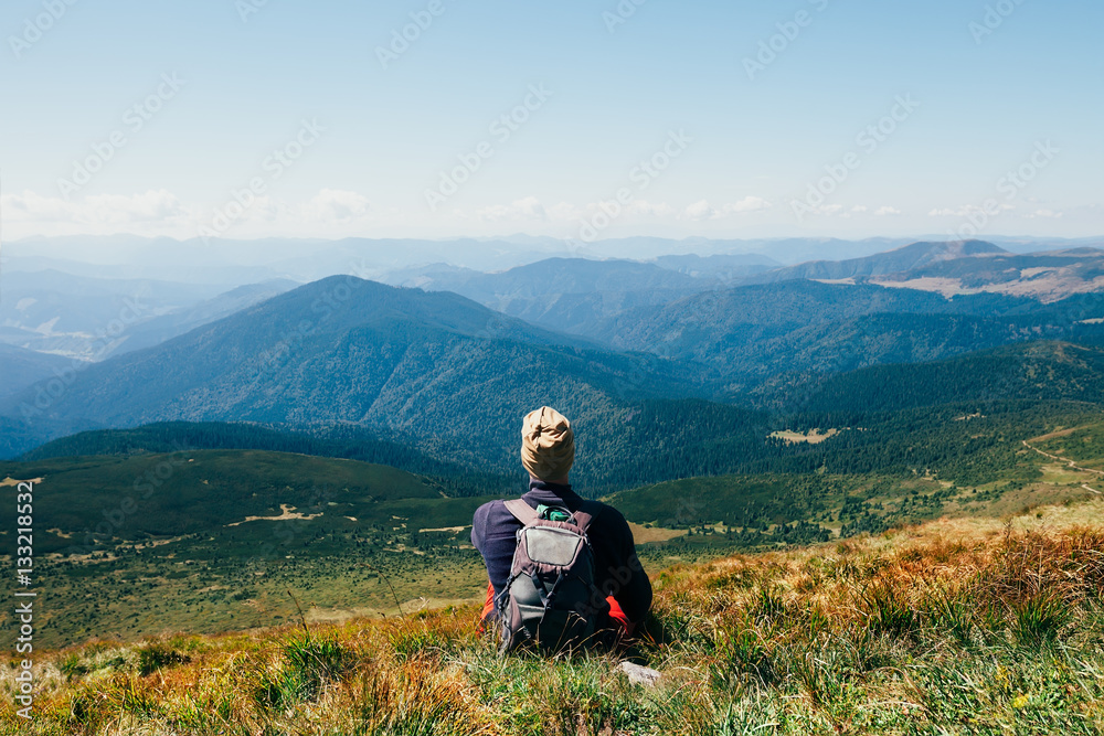 Handsomeyoung man sitting on rocky cliff and enjoying nature Handsomeyoung man sitting on rocky cliff and enjoying nature