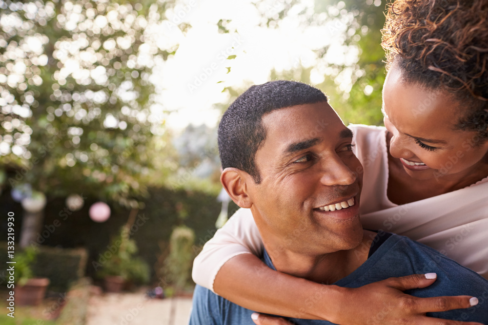 Young black couple piggyback in garden looking at each other Young black couple piggyback in garden looking at each other