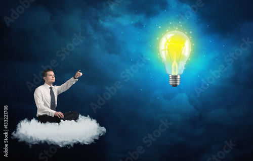 Man sitting on cloud looking at a lightbulb