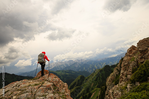 successful woman backpacker hiking on mountain peak cliff
