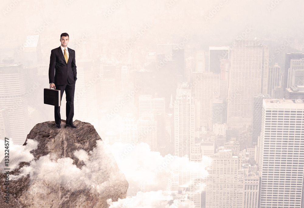 Happy businessman standing on stone top Happy businessman standing on stone top