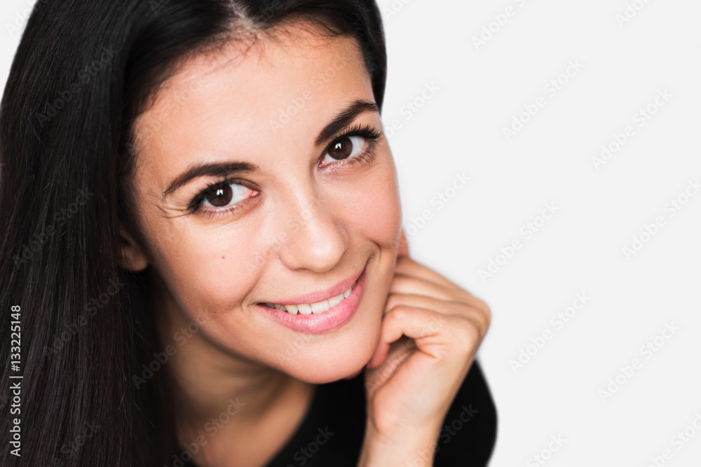 Close up portrait of brunette cute woman with beauty smile, with hand face. Young happy pretty woman wearing black sweater on light grey background. Positive and happiness mood. Close up portrait of brunette cute woman with beauty smile, with hand face. Young happy pretty woman wearing black sweater on light grey background. Positive and happiness mood.