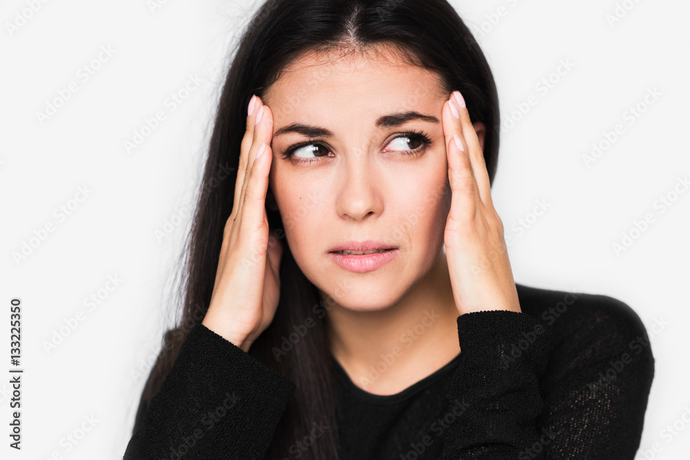 Close up portrait of brunette pretty woman with headache touching her temples look at one side. Beautiful woman stressed and worry in black sweater on light grey background. Healthcare and medicine. Close up portrait of brunette pretty woman with headache touching her temples look at one side. Beautiful woman stressed and worry in black sweater on light grey background. Healthcare and medicine.