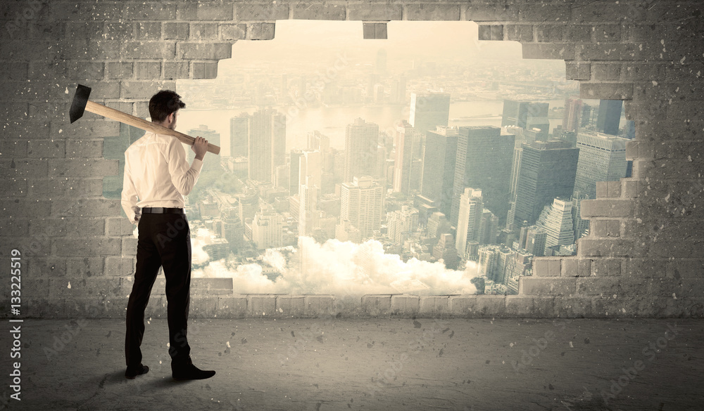 Business man hitting wall with hammer on city view Business man hitting wall with hammer on city view