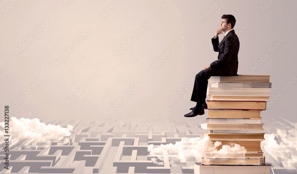 Businessman sitting on books in labirynth
