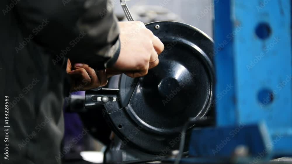 Mechanic worker man grind rusty bolts with electric grinder tool in manufactory