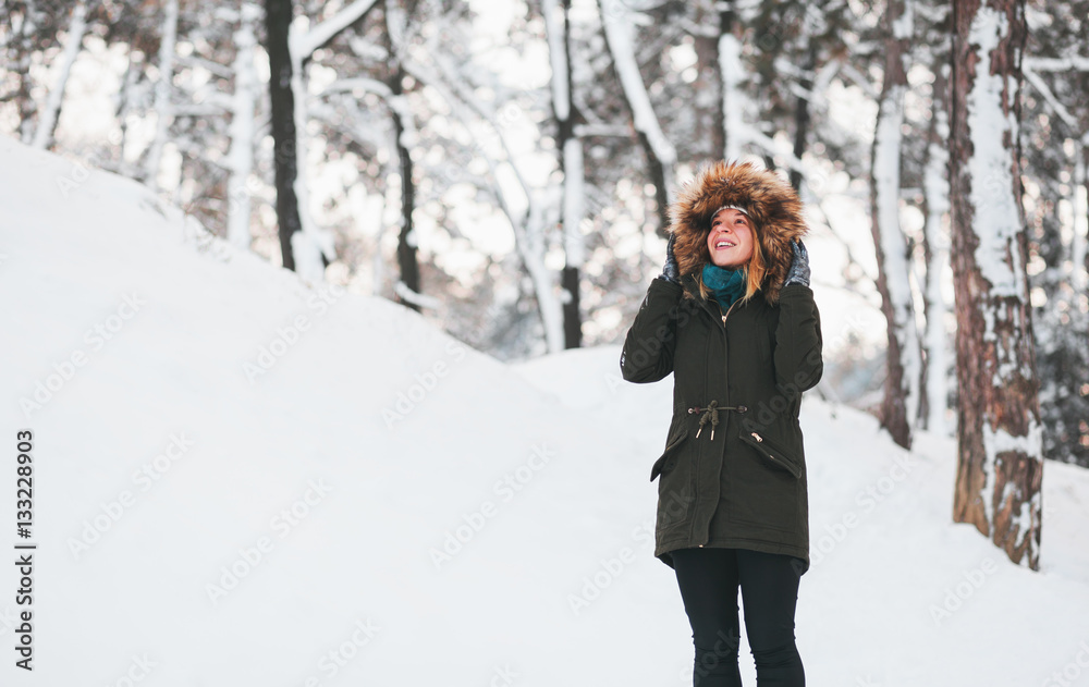 Young cute woman standing in the snow in the park