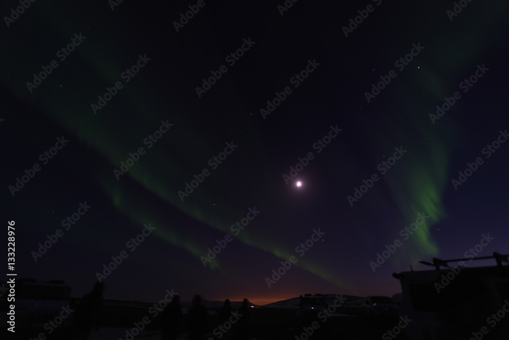 iceland northern lights with moon and Reykjavik on the horizon