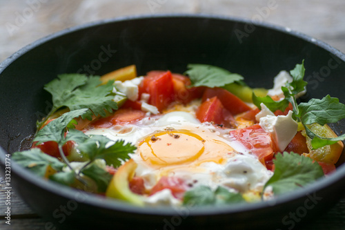 fried egg in a pan with tomatoes and greens