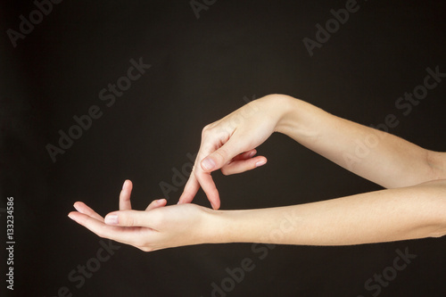 Женские руки жестикулируют на темном фоне.
