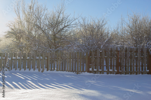 Winter snowy vintage old backyard wooden fence, beautiful shadows on sunny snow photo