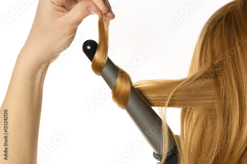 Woman with red hair makes a curling hair by herself isolated on white