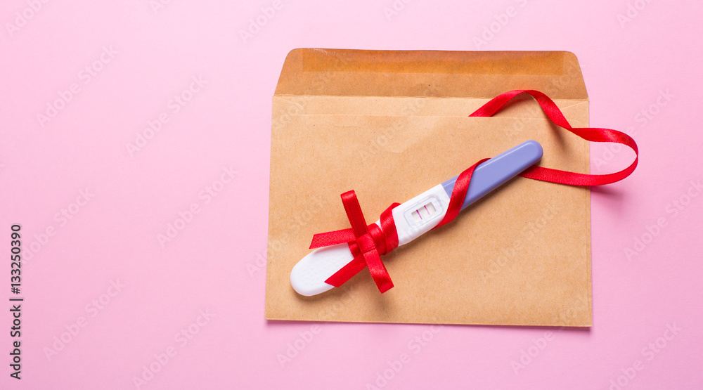 letter with a positive pregnancy test on a pink background letter with a positive pregnancy test on a pink background