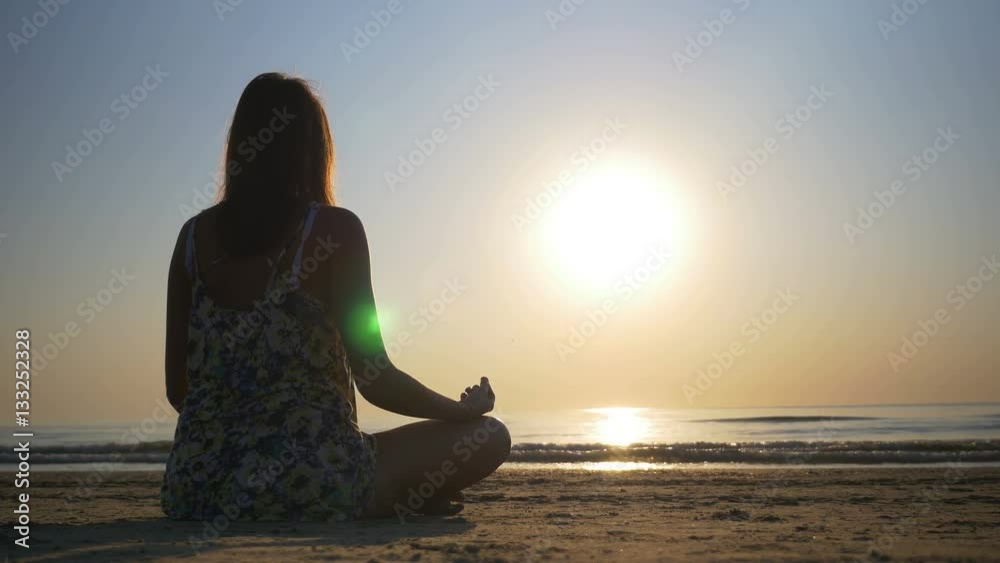Woman meditating on the beach towards the sea Woman meditating on the beach towards the sea