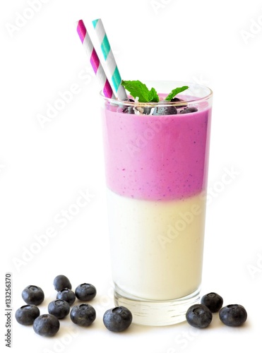 Layered blueberry and coconut smoothie with mint and scattered berries on a white background