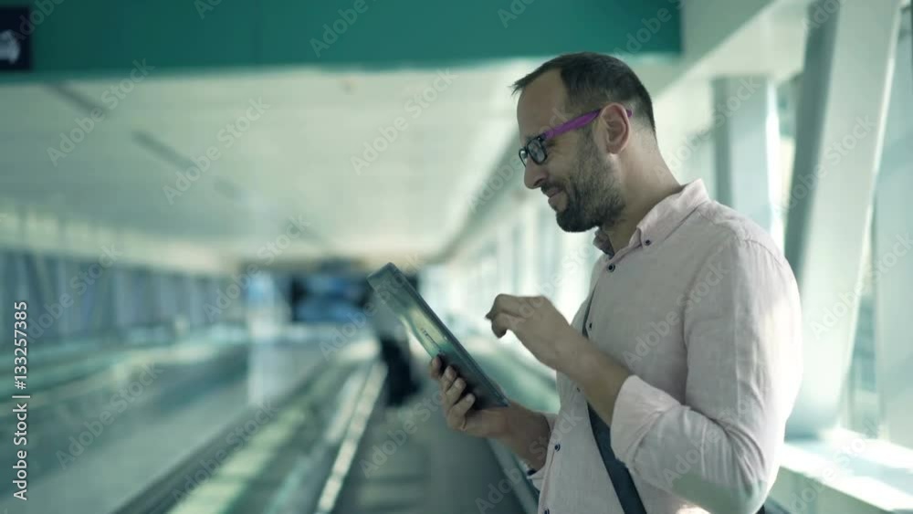 Young, happy man using tablet computer while riding escalator stairs
Young, happy man using tablet computer while riding escalator stairs