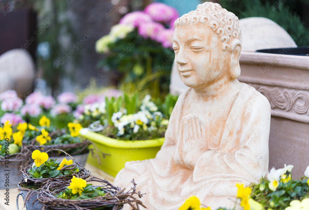 Harmonisch gestalteter Garten mit Buddha Skulptur und bunten Pflanzen