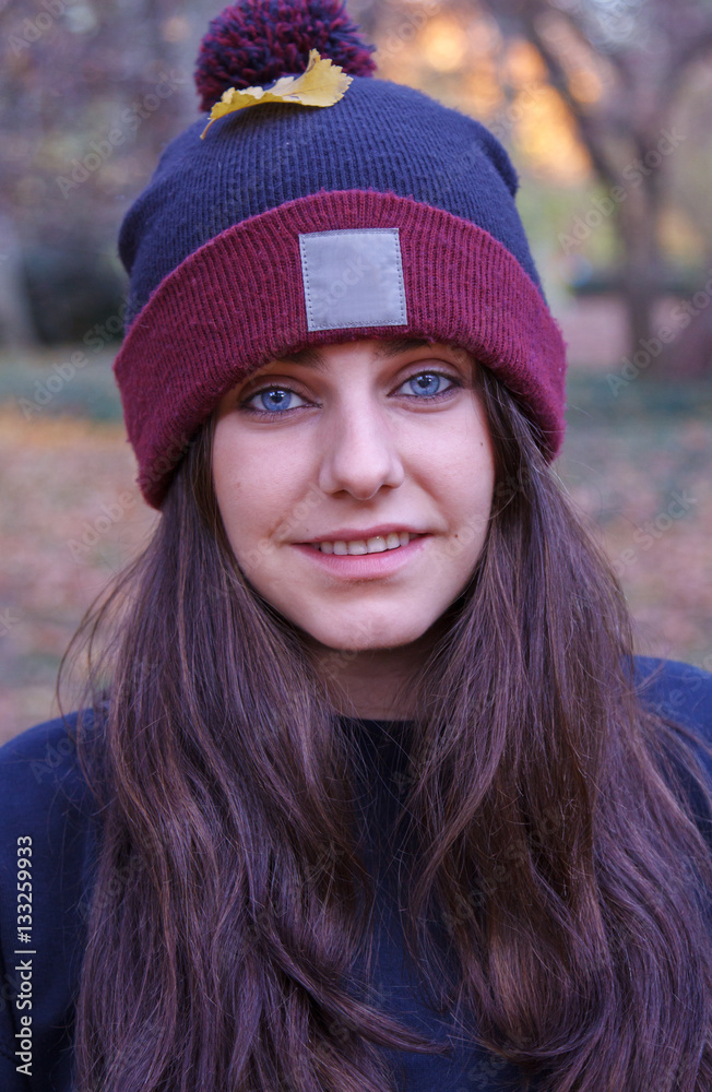 Portrait of a young Caucasian woman with blue eyes dressed in a wool cap with a white space where you can add information. She is in the field on an autumn day. Portrait of a young Caucasian woman with blue eyes dressed in a wool cap with a white space where you can add information. She is in the field on an autumn day.