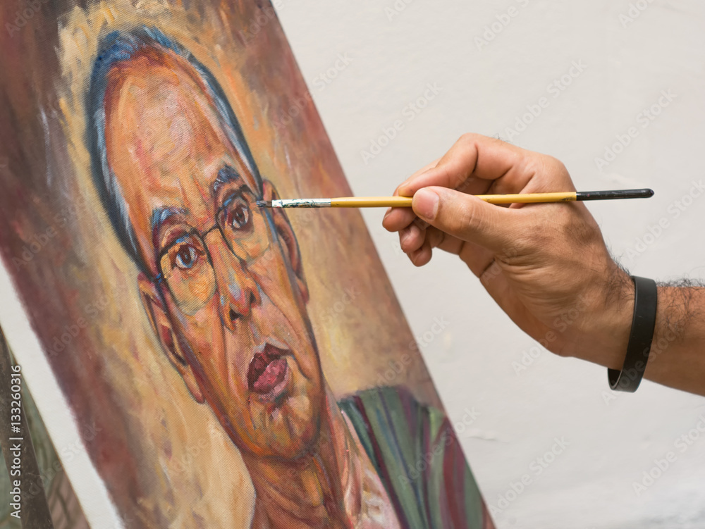 Naklejka premium Closeup artist hand holding paint brush painting portrait of asi
