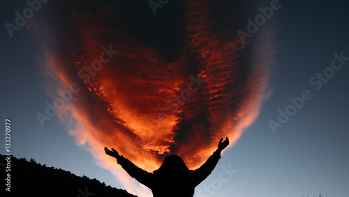 Person raising their hands out in front of red cloud
