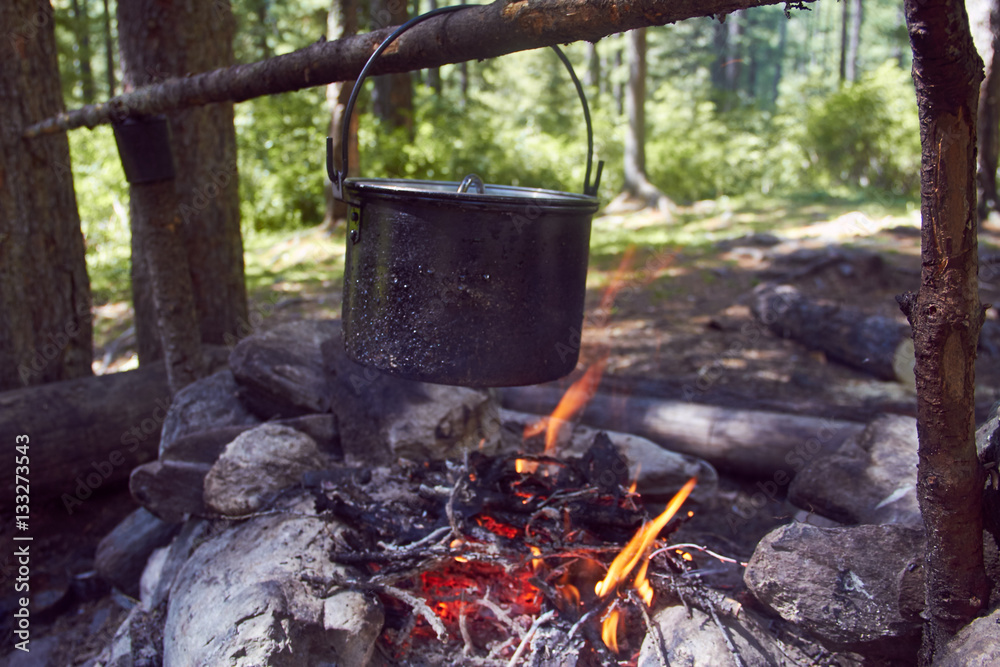 Cauldron boils on the fire in the forest. In marching a saucepan preparing food. Adventure tourism, camping, cooking on a fire. Survival in the forest. Stalker Cauldron boils on the fire in the forest. In marching a saucepan preparing food. Adventure tourism, camping, cooking on a fire. Survival in the forest. Stalker