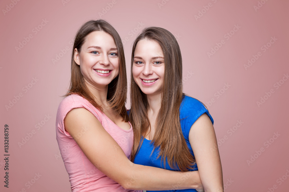 Studio portait of young twin sisters embracing Studio portait of young twin sisters embracing