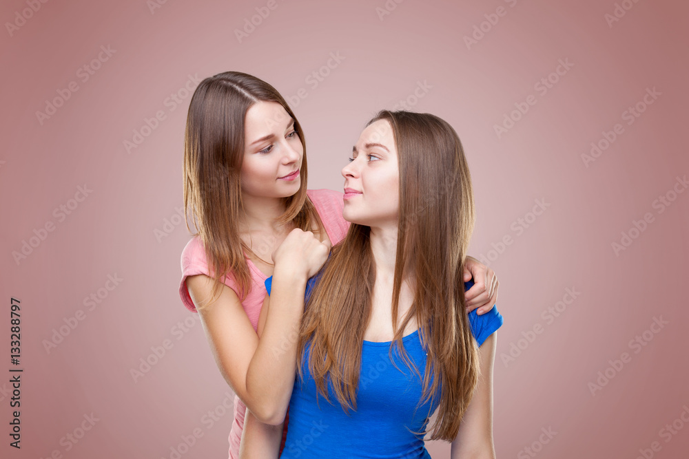 Studio portait of young twin sisters embracing