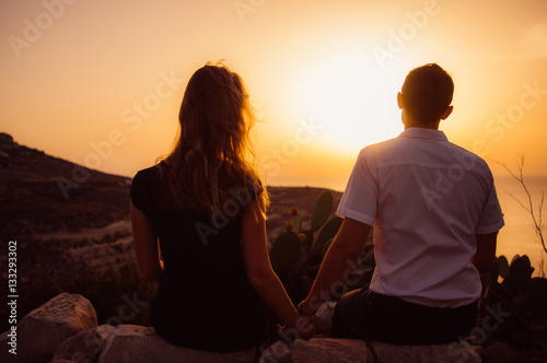 Couple sitting on rock in the evening on the seaside