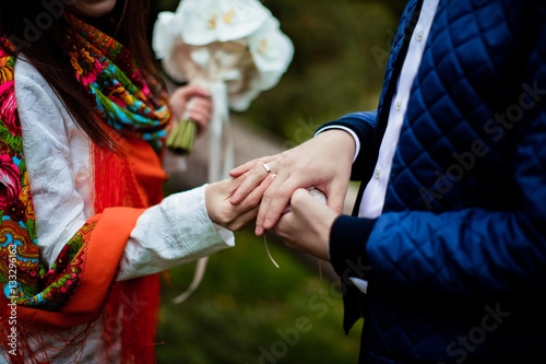 Hands with rings Groom putting golden ring on bride's finger during wedding ceremony