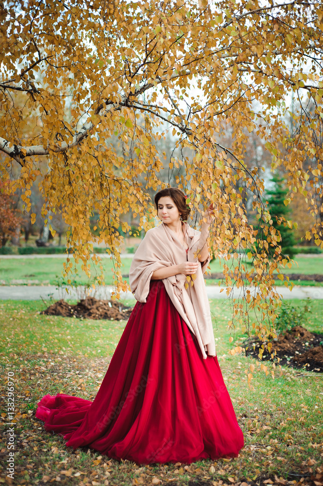 beautiful girl in a red dress in the autumn forest