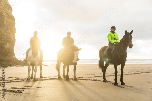 People with horses on the beach on a cloudy day