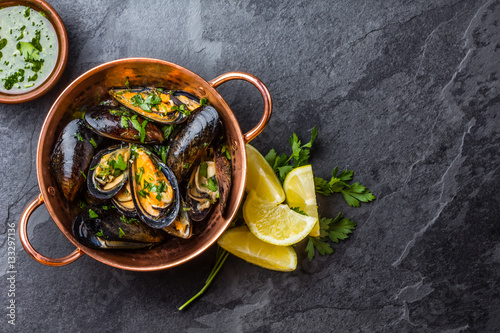 Mussels in copper bowl, lemon, herbs sauce and white wine.