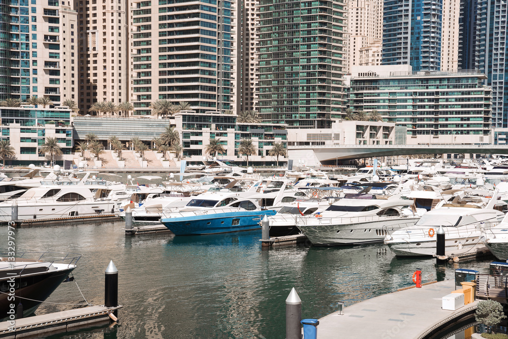 Dubai harbor with boats and yachts on a mooring, on skyscrapers background