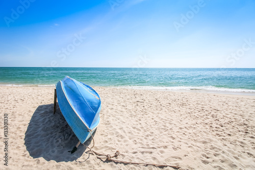 Small blue sailing boat upside down lays on the beach