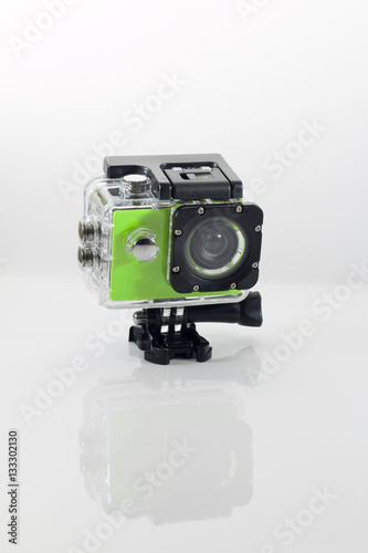 Isolated green action cam against a white background casting a reflection