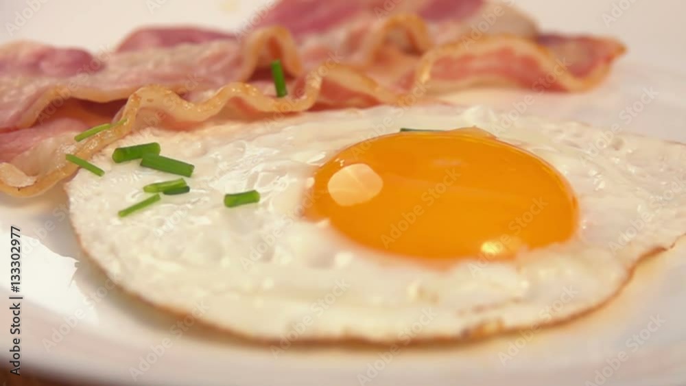 Chives falls on the white plate with egg and bacon Chives falls on the white plate with egg and bacon