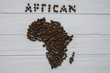 Map of the Africa made of roasted coffee beans laying on white wooden textured background and space for text