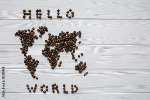 Map of the world made of roasted coffee beans laying on white wooden textured background with signature and space for text
