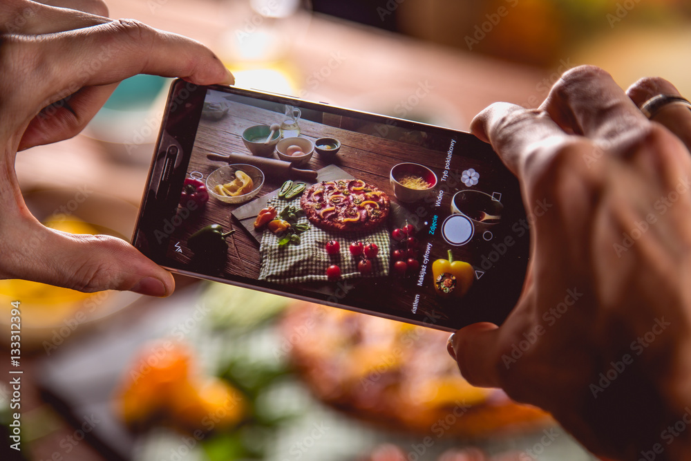 Man is taking photo fresh and tasty pizza on wooden table Man is taking photo fresh and tasty pizza on wooden table