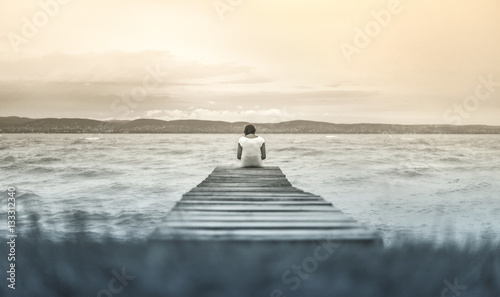 Lonely girl sitting at the pier photo